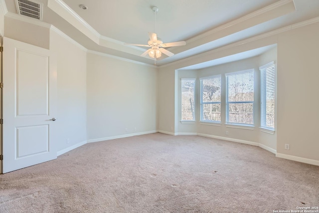 carpeted empty room featuring a tray ceiling, ornamental molding, and ceiling fan