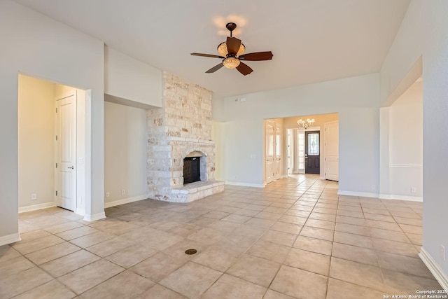 unfurnished living room with ceiling fan with notable chandelier, a stone fireplace, and light tile patterned floors