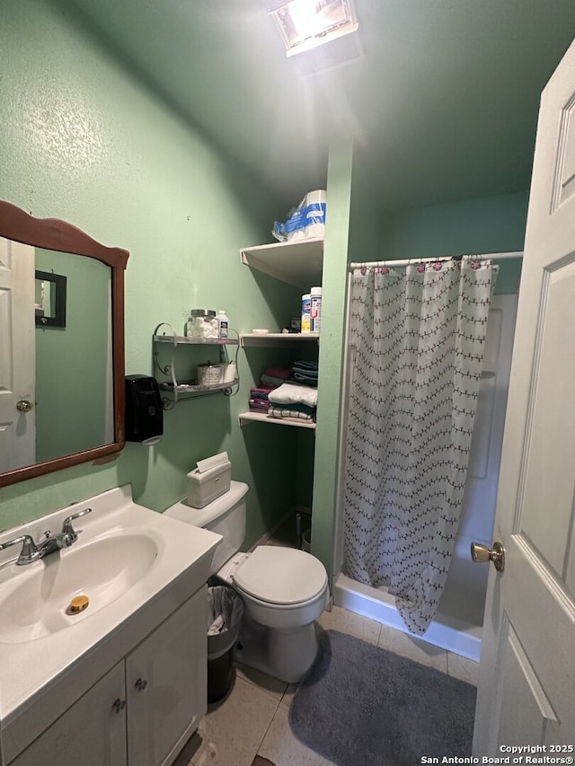 bathroom with tile patterned flooring, vanity, toilet, and walk in shower