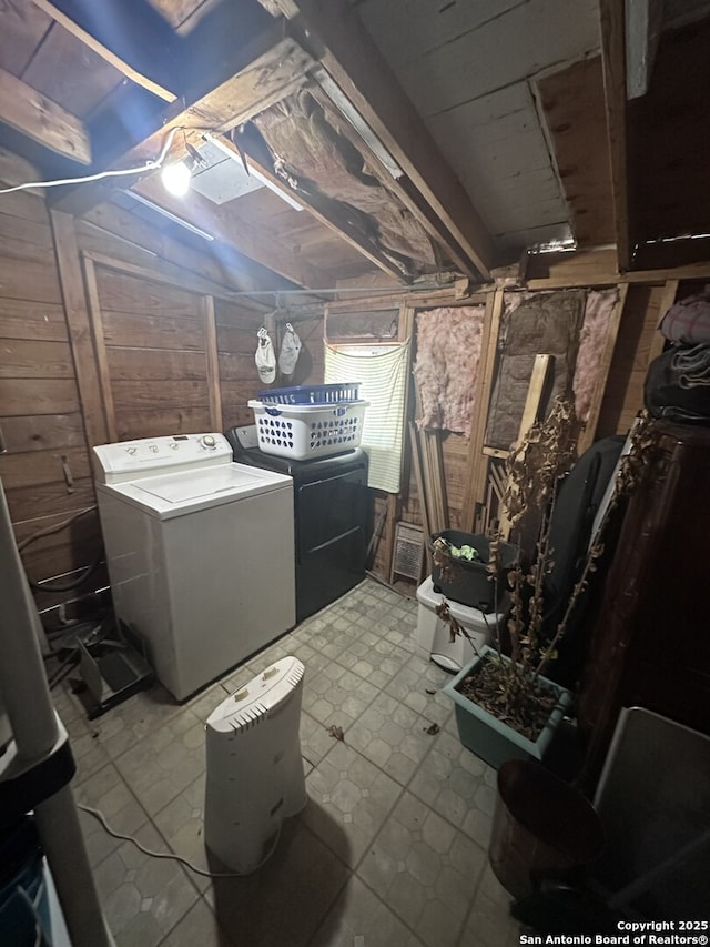 clothes washing area featuring washer / clothes dryer and wood walls