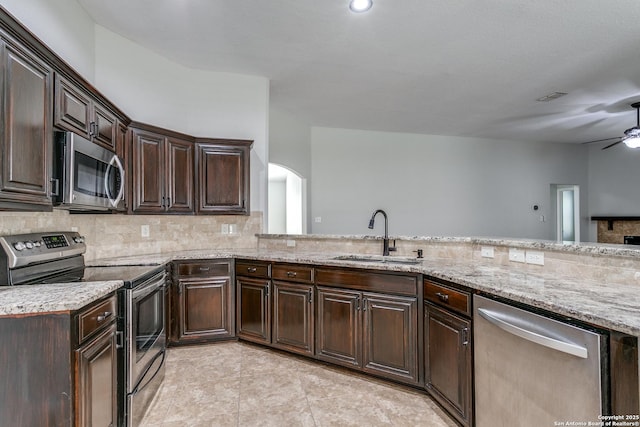 kitchen with appliances with stainless steel finishes, sink, light tile patterned floors, kitchen peninsula, and dark brown cabinets