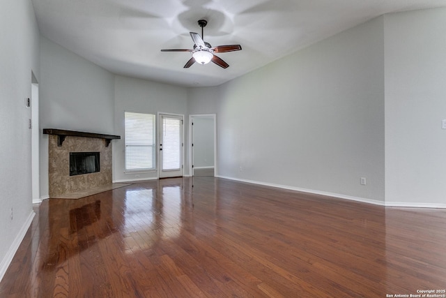 unfurnished living room featuring ceiling fan, a premium fireplace, and dark hardwood / wood-style flooring