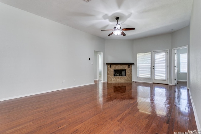 unfurnished living room with dark wood-type flooring, a premium fireplace, and ceiling fan