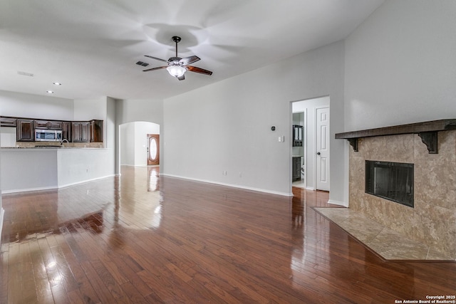 unfurnished living room featuring dark hardwood / wood-style flooring, a fireplace, and ceiling fan