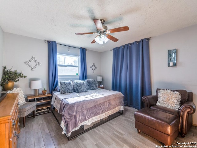 bedroom with ceiling fan, light hardwood / wood-style floors, and a textured ceiling