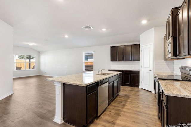 kitchen with sink, stainless steel appliances, tasteful backsplash, an island with sink, and vaulted ceiling