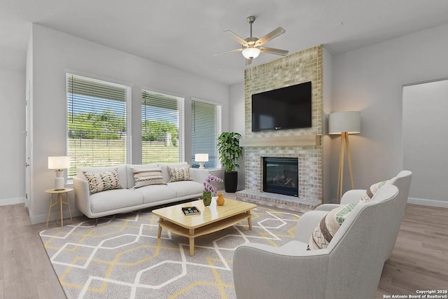 living room with ceiling fan, a fireplace, and light hardwood / wood-style flooring