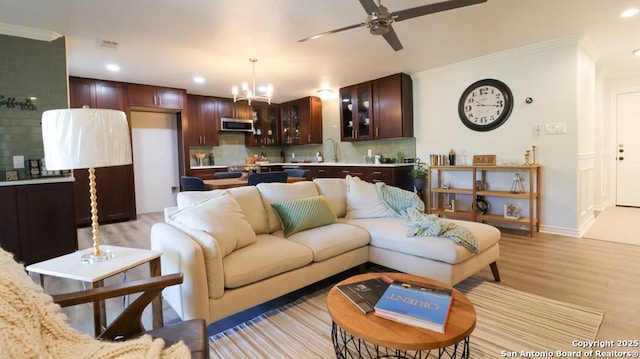 living room featuring crown molding, sink, ceiling fan with notable chandelier, and light hardwood / wood-style floors