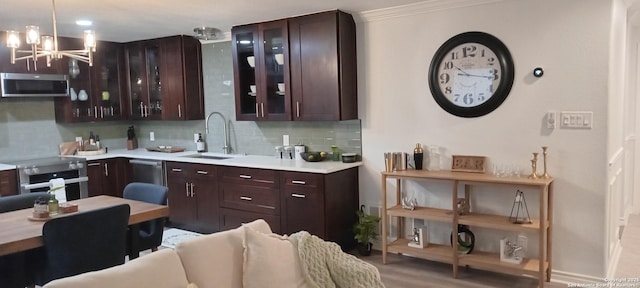 kitchen with sink, an inviting chandelier, crown molding, stainless steel appliances, and decorative backsplash