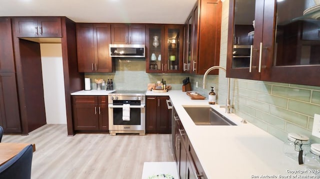 kitchen with sink, backsplash, stainless steel appliances, and light hardwood / wood-style floors