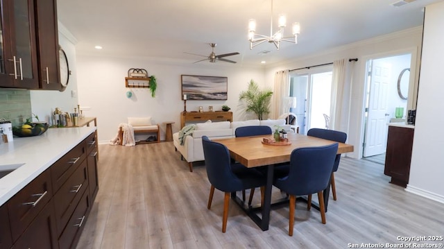 dining room featuring crown molding, light hardwood / wood-style flooring, and ceiling fan with notable chandelier