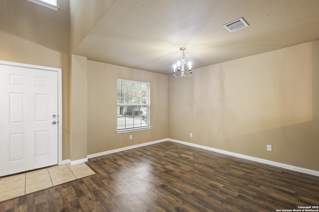 entrance foyer with baseboards, wood finished floors, visible vents, and a chandelier