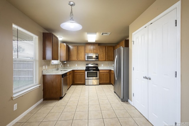 kitchen with light tile patterned flooring, sink, appliances with stainless steel finishes, pendant lighting, and backsplash