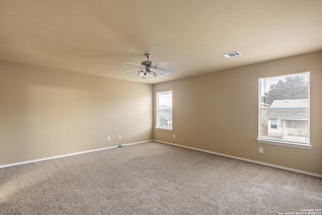 empty room with visible vents, carpet floors, baseboards, and ceiling fan