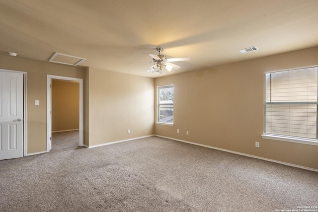 unfurnished room with visible vents, carpet flooring, attic access, and baseboards