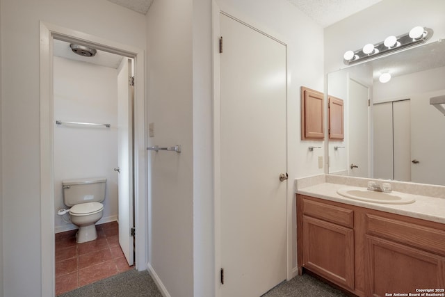 bathroom featuring vanity, a textured ceiling, and toilet