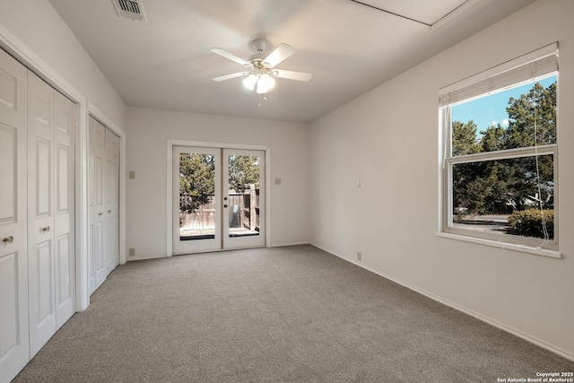 unfurnished bedroom featuring multiple windows, light carpet, french doors, and ceiling fan