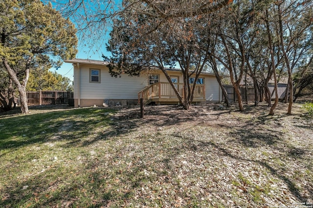 rear view of property featuring a wooden deck and a lawn