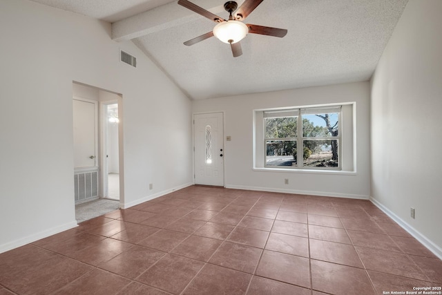 tiled foyer entrance with ceiling fan, vaulted ceiling with beams, and a textured ceiling