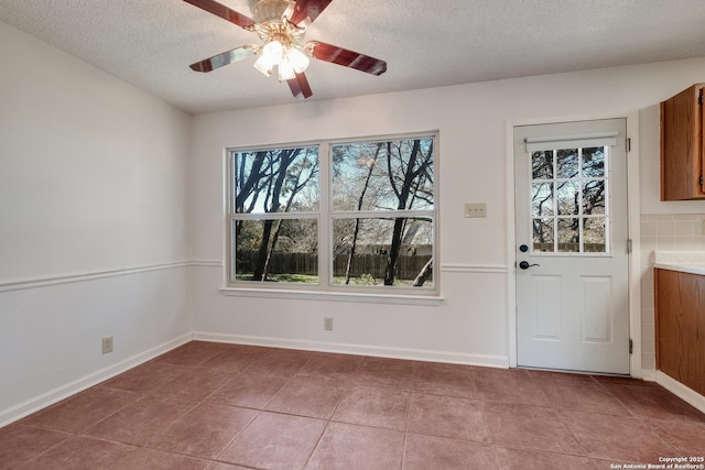 unfurnished dining area with tile patterned flooring, ceiling fan, and a textured ceiling