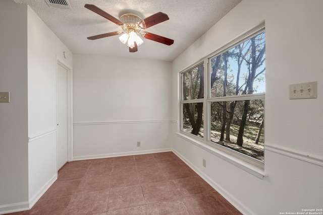 tiled empty room with ceiling fan and a textured ceiling