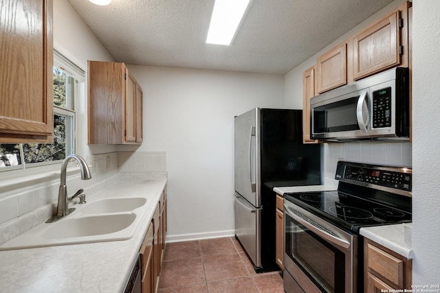 kitchen featuring sink, a textured ceiling, light tile patterned floors, stainless steel appliances, and decorative backsplash