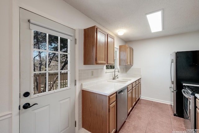 kitchen with sink, a textured ceiling, light tile patterned floors, stainless steel appliances, and backsplash