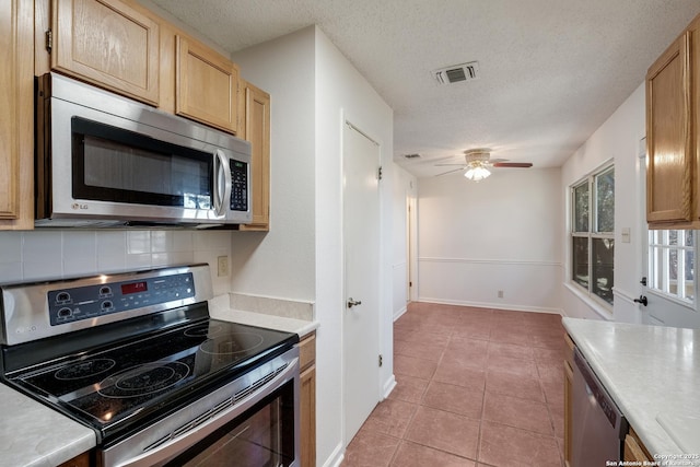 kitchen featuring light tile patterned floors, ceiling fan, backsplash, stainless steel appliances, and a textured ceiling