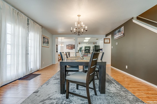 dining area with light hardwood / wood-style floors and a notable chandelier