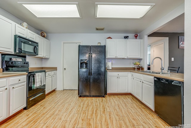 kitchen with white cabinets, sink, light hardwood / wood-style flooring, and black appliances