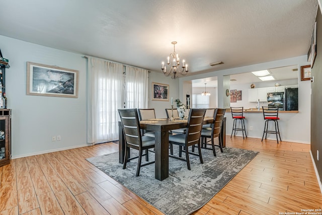 dining area with an inviting chandelier and light wood-type flooring