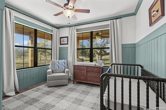 bedroom with ceiling fan and a crib