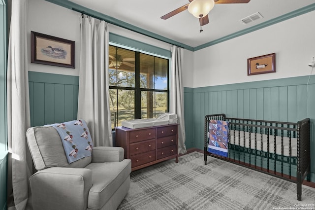 carpeted bedroom featuring a crib and ceiling fan