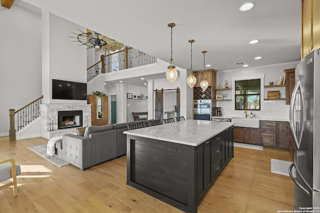 kitchen featuring sink, decorative backsplash, a center island, stainless steel appliances, and a barn door