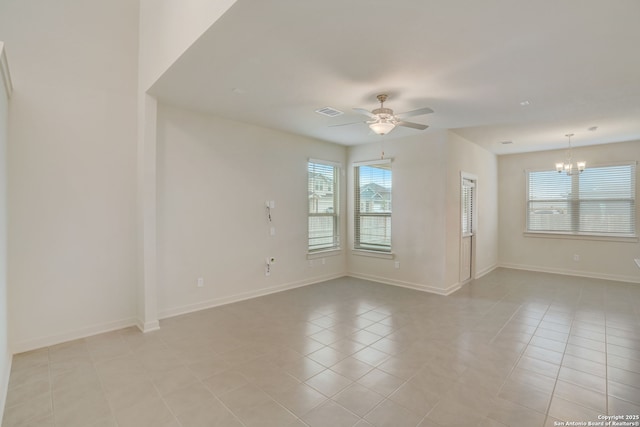 spare room featuring ceiling fan with notable chandelier and light tile patterned floors