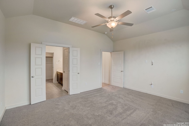 unfurnished bedroom with vaulted ceiling, light colored carpet, ceiling fan, and ensuite bathroom