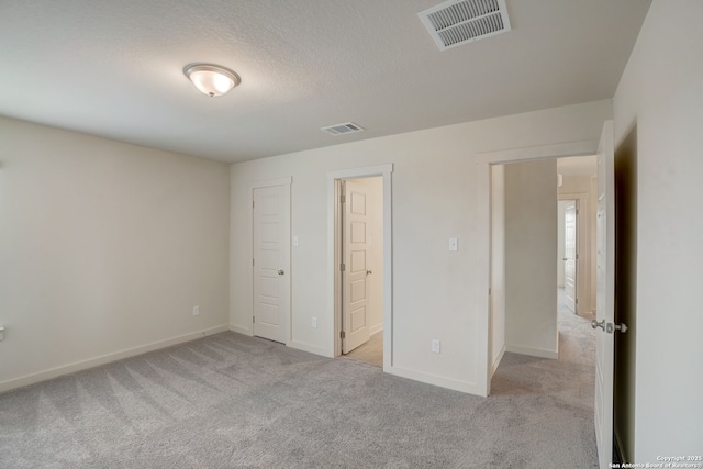 unfurnished bedroom with a closet, light carpet, and a textured ceiling