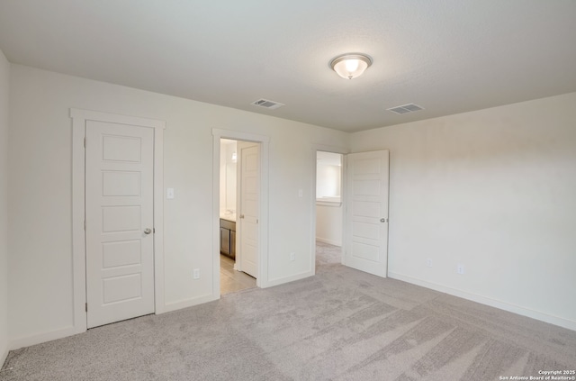 unfurnished bedroom featuring light carpet, connected bathroom, and a closet