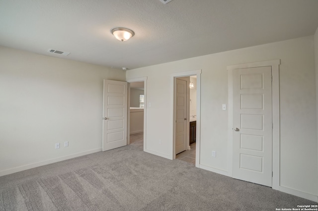 unfurnished bedroom with connected bathroom and light colored carpet