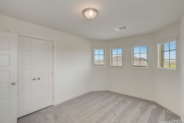 unfurnished bedroom featuring light carpet and a closet