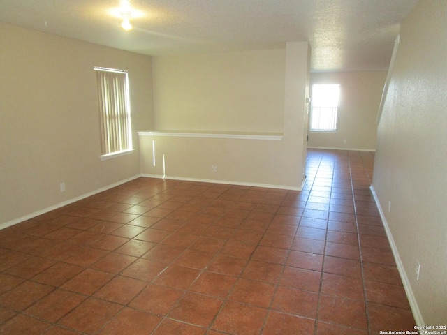 empty room with dark tile patterned flooring and a textured ceiling