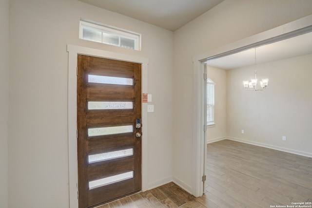 foyer entrance with light hardwood / wood-style floors and a chandelier