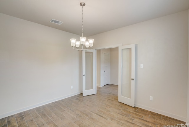 empty room with an inviting chandelier and light hardwood / wood-style floors