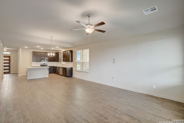 unfurnished living room featuring ceiling fan with notable chandelier and light wood-type flooring