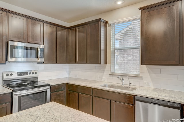 kitchen featuring dark brown cabinetry, sink, backsplash, and stainless steel appliances