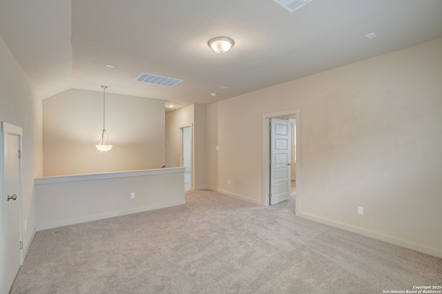 carpeted empty room featuring vaulted ceiling and a textured ceiling