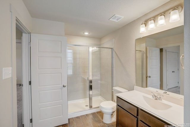 bathroom with vanity, a shower with shower door, and toilet