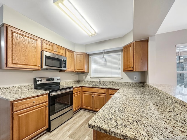 kitchen featuring plenty of natural light, light wood-style flooring, appliances with stainless steel finishes, and a sink