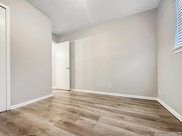 spare room with baseboards and wood finished floors