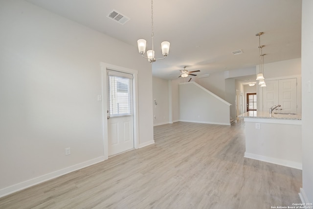 unfurnished room featuring ceiling fan with notable chandelier and light wood-type flooring